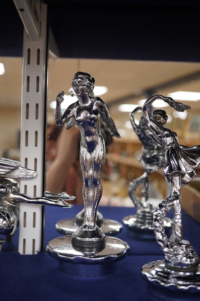 Five chrome car mascots in the form of female dancing figures, three mounted on threaded radiator caps, one with a registration number: 675619, one a stylised Art Deco winged female figure astride a globe. Condition - fa